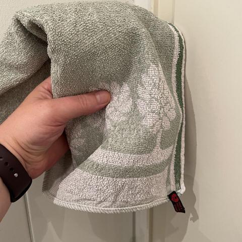 Eine Hand hält ein grünes Handtuch.