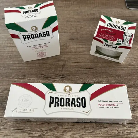 Drei Proraso-Produkte in rechteckigen Verpackungen mit italienischer Flaggenoptik und großem Schriftzug auf Holzoberfläche